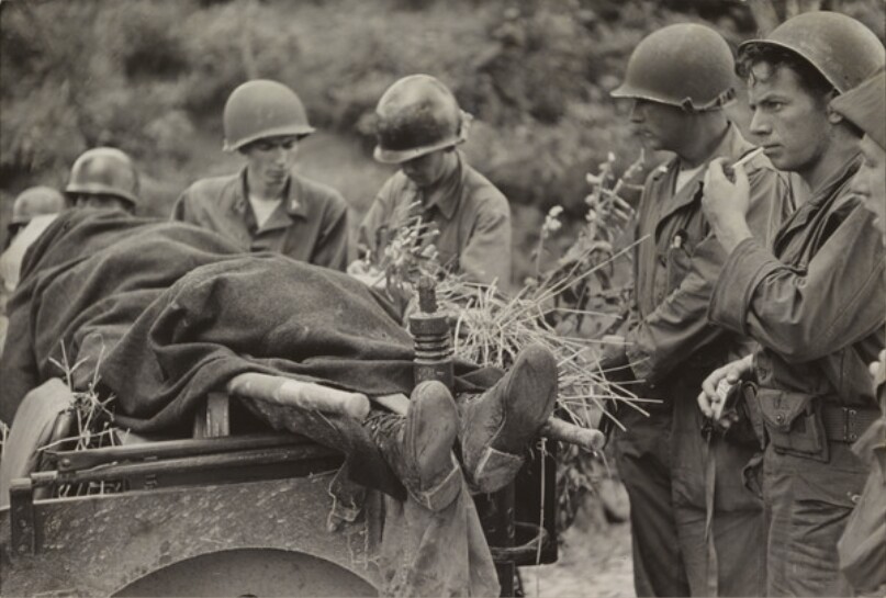 The first American killed in the Korean War is surrounded by his comrades