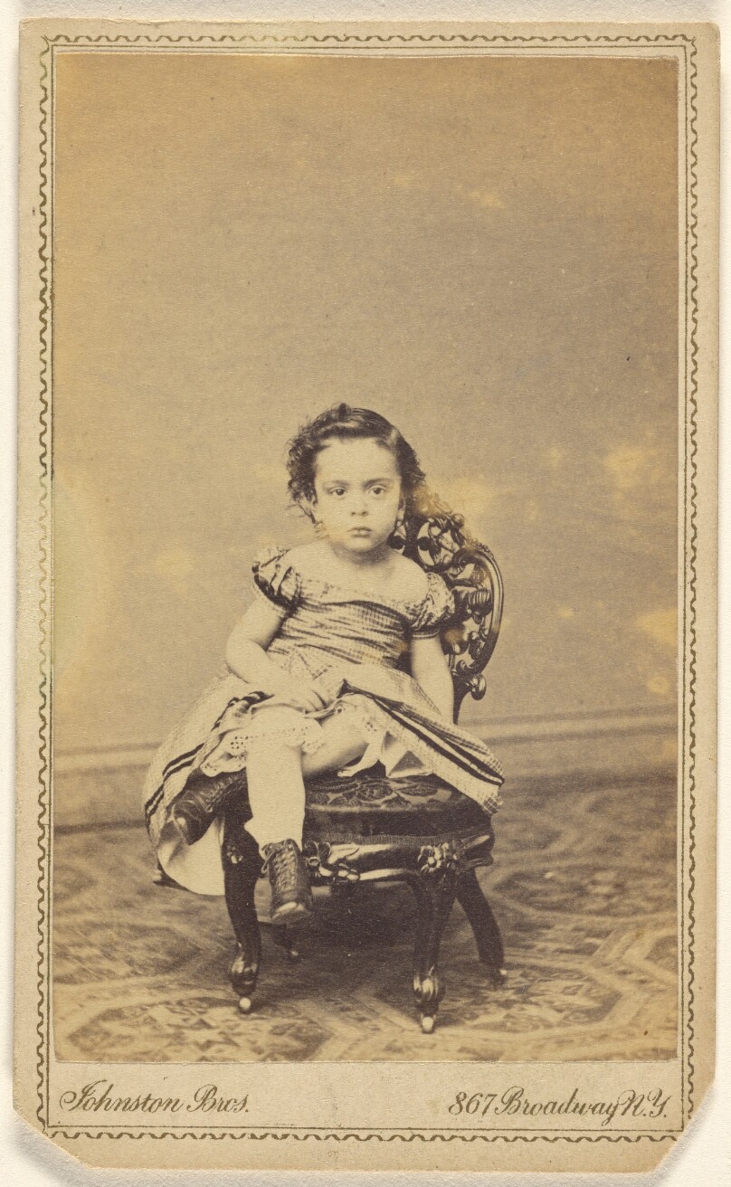 [Unidentified little girl seated in a small chair]