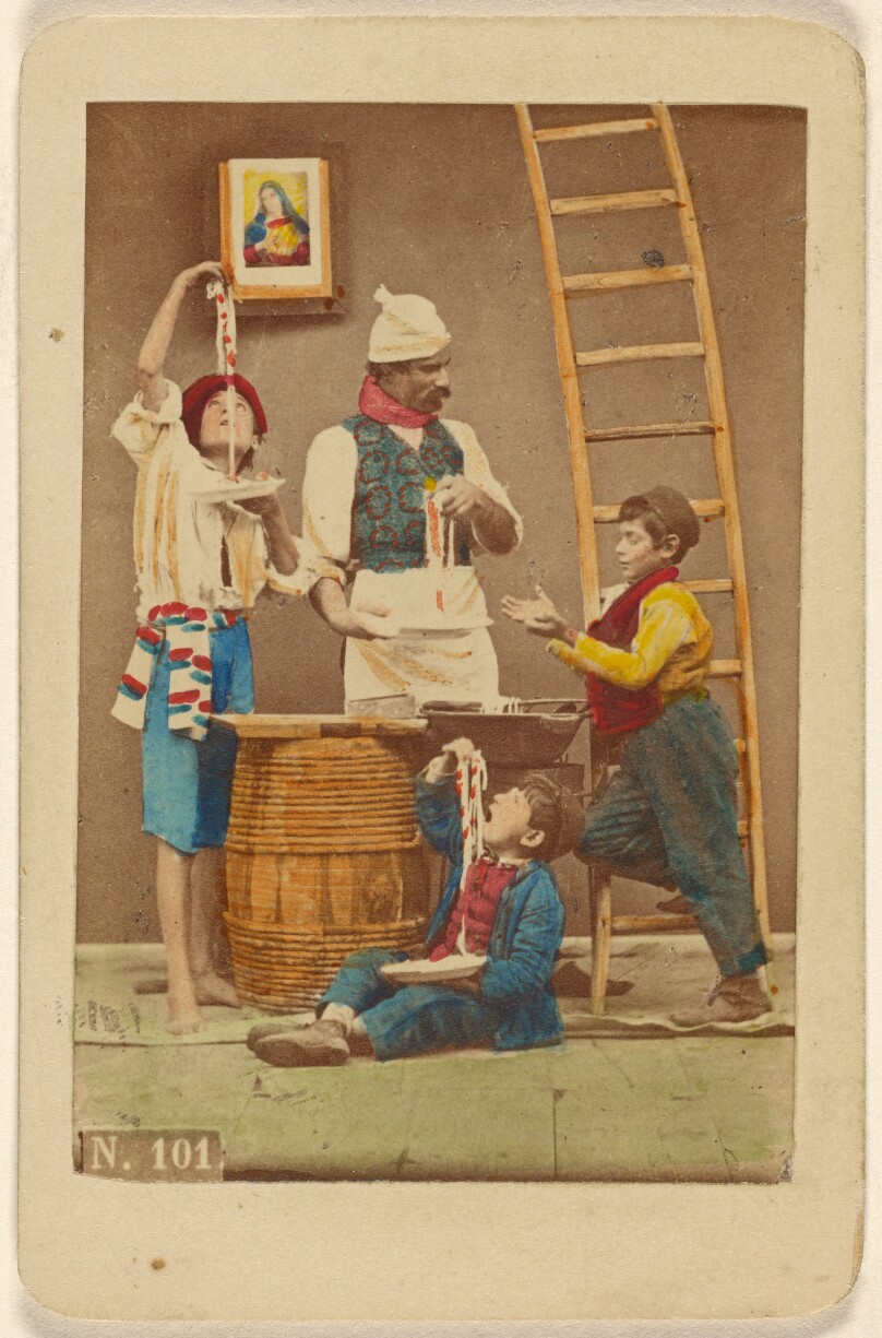 [Unidentified man with moustache making pasta, three boys either eating it or helping him make it]