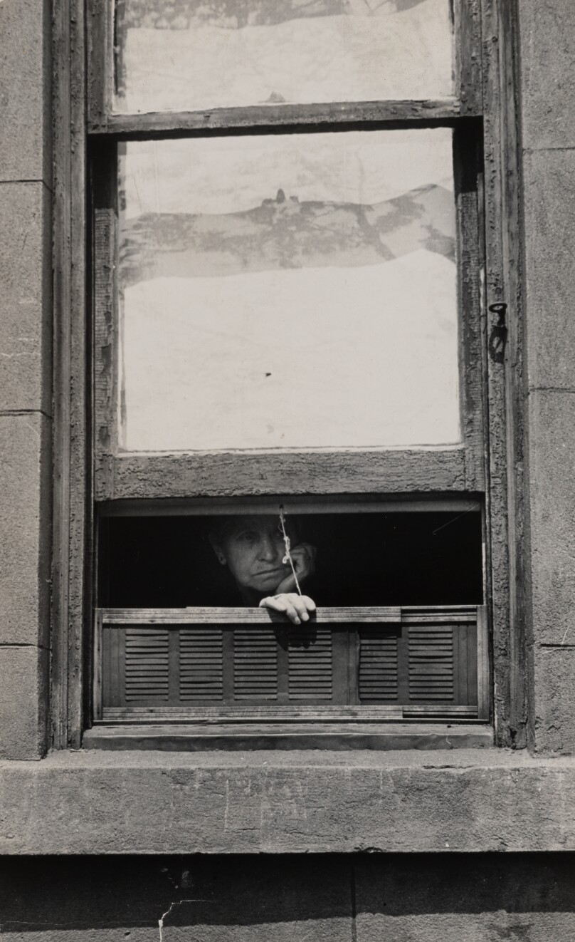 [Woman looking through a window]