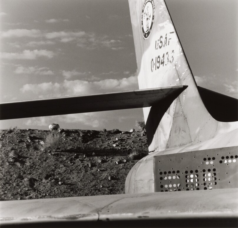 Untitled [looking back over airplane tail towards hill and sky]