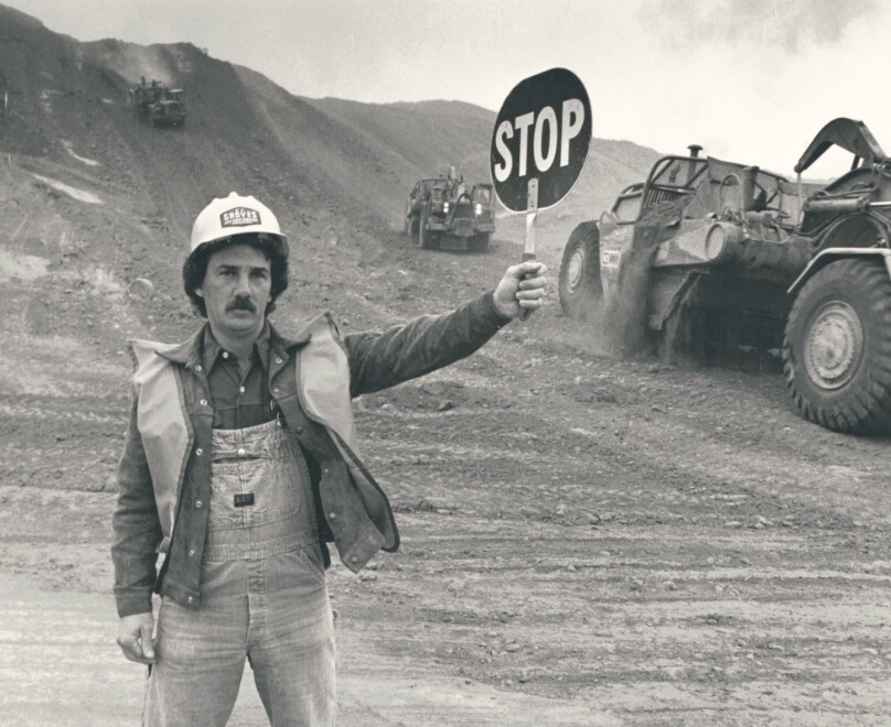 Construction Worker Directing Equipment Holding Stop Sign