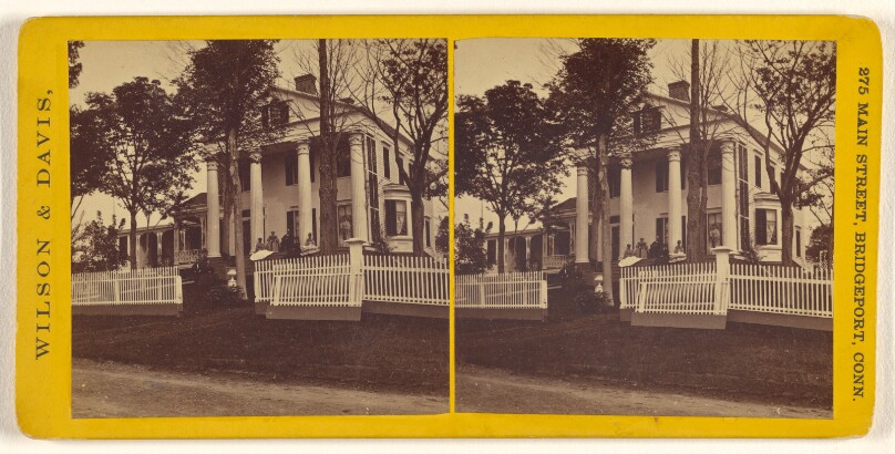 [Long view of large house with columns, family on front porch]