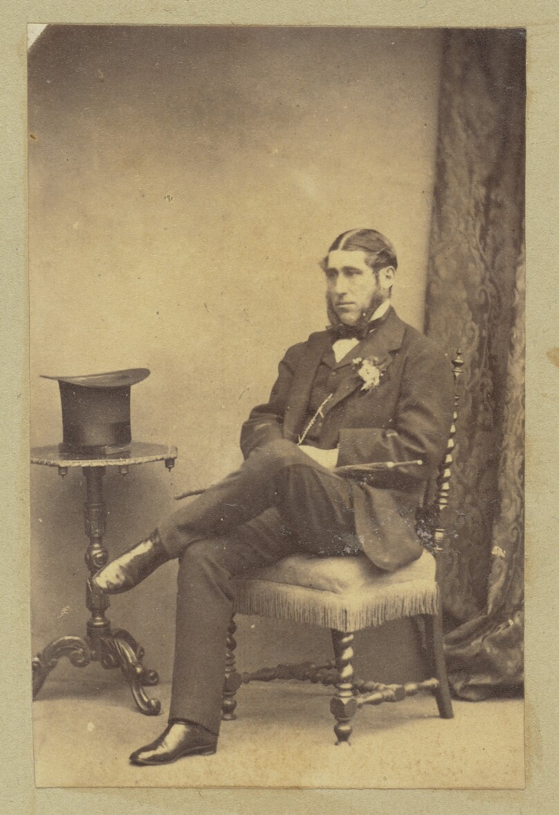 [Portrait of seated man with top hat on table]