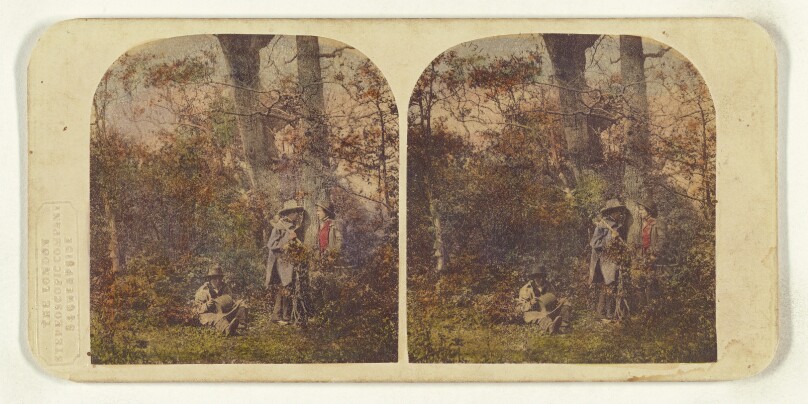 [Three men in the woods, two standing, one seated]