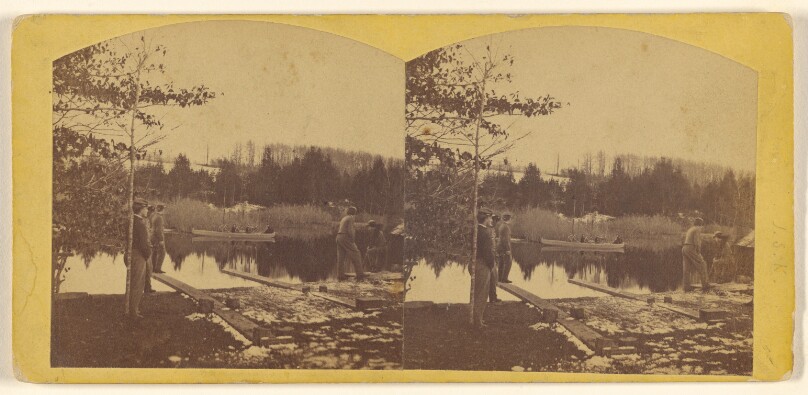 [Several people at a pond, one group in canoe]