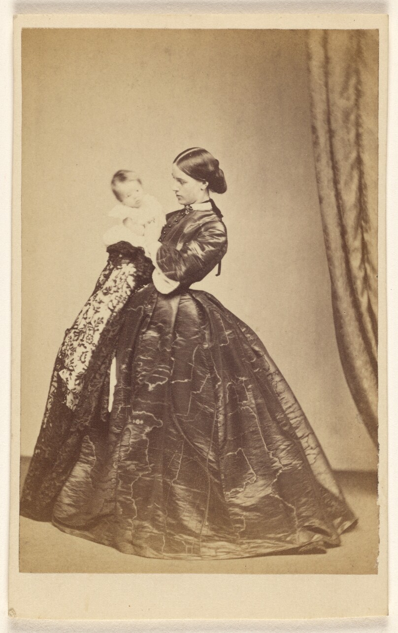 [Unidentified woman holding a child, standing]