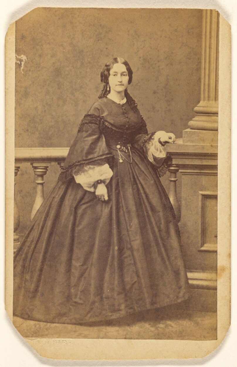 [Unidentified woman in long dress, standing]