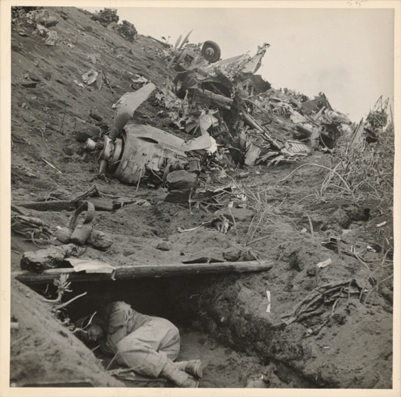 Wreckage on beach as man sleeps in shelter after one of fierce battle against Japanese for Iwo Jima during WWII