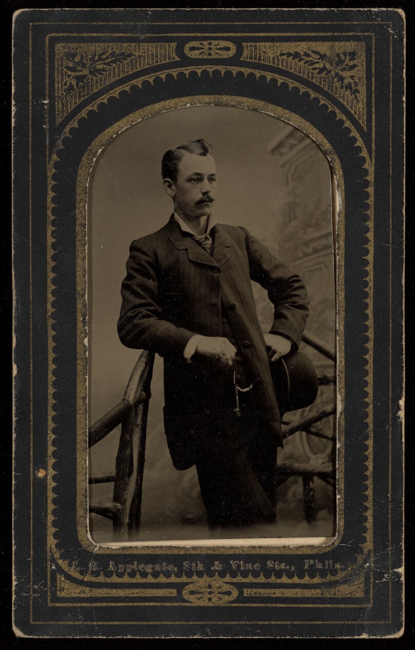 [Unidentified man with moustache standing, holding a derby]