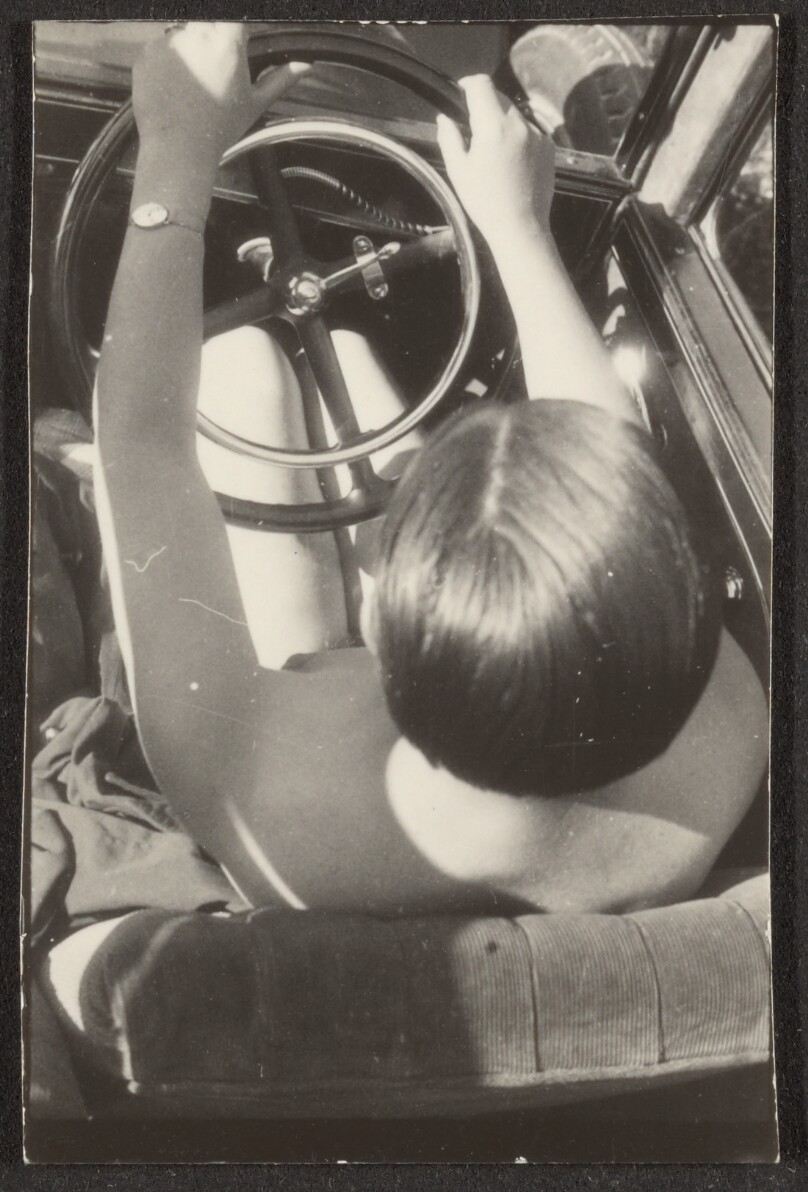 [Contact print from single Leica negative: nude woman in driver's seat of car from above]