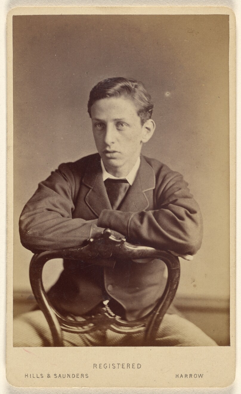 [Unidentified young man seated, with arms on chair back]