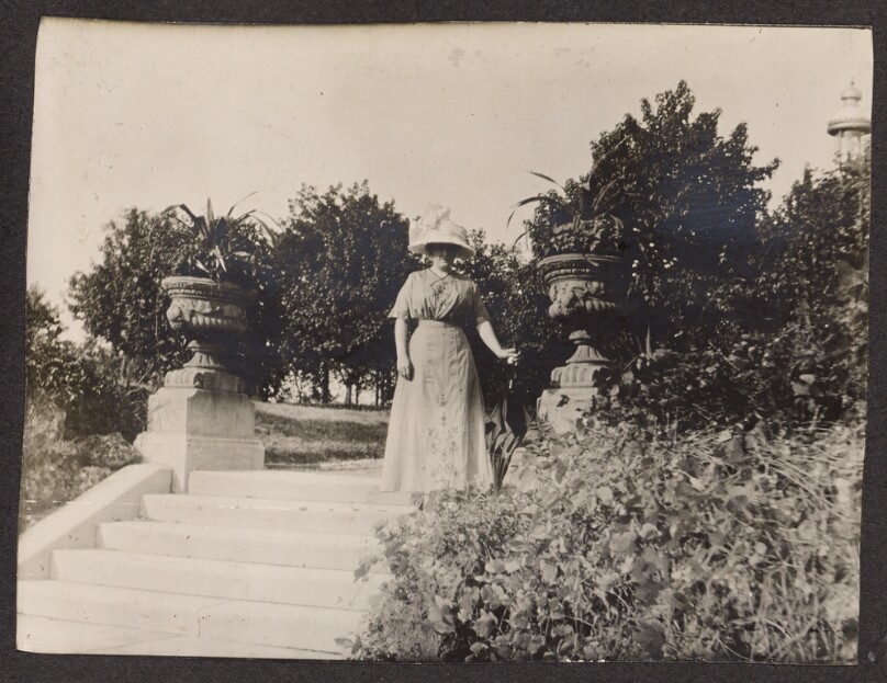 [Woman standing between stone planters]