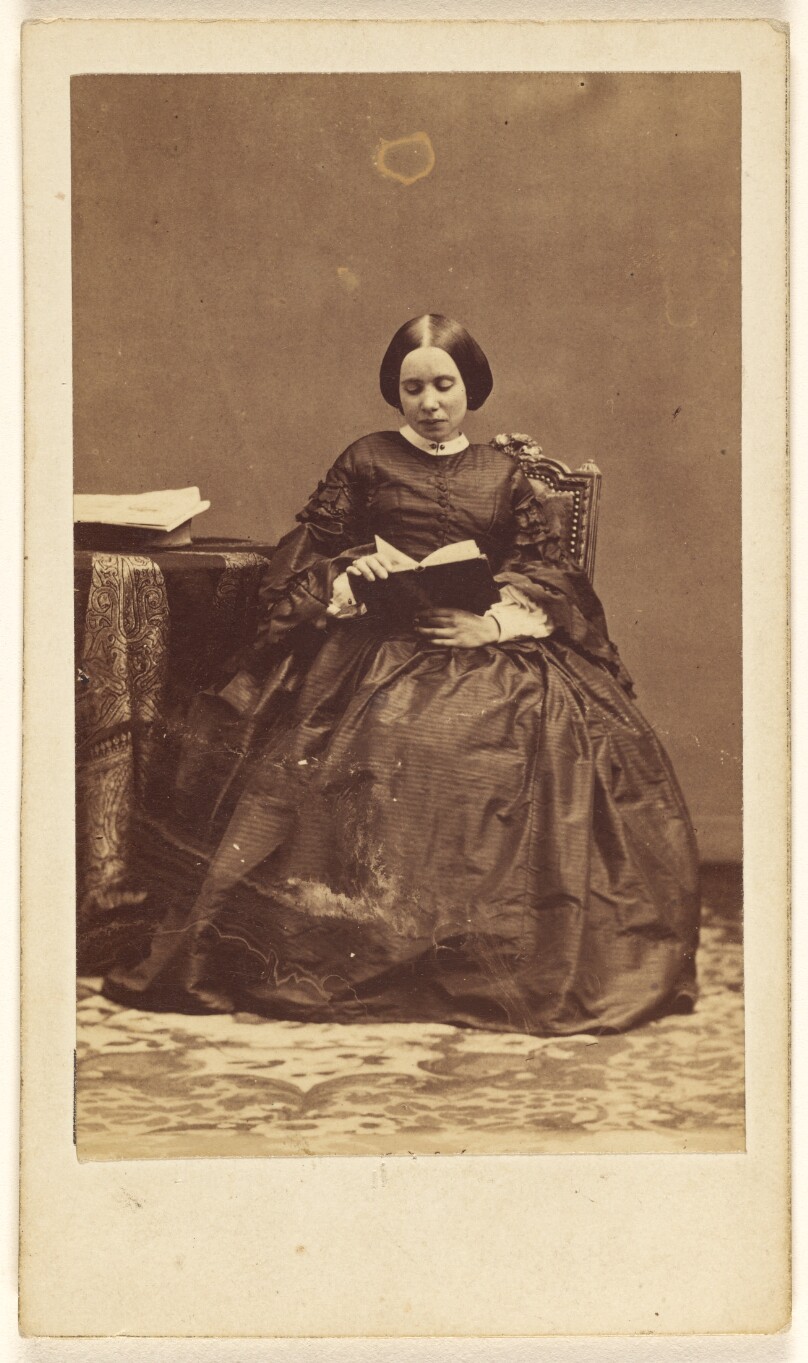 [Unidentified woman seated, reading a book]