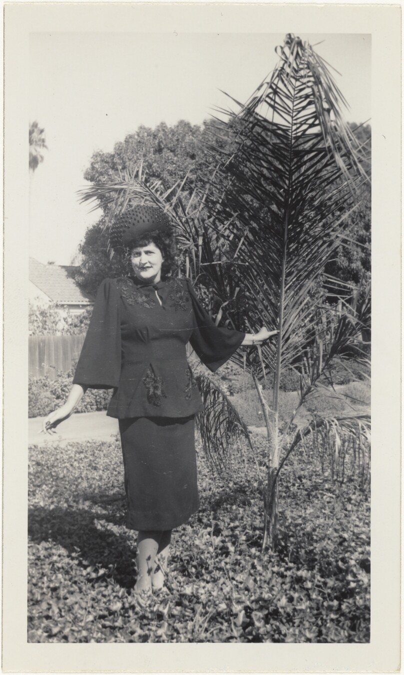 [Woman beside palm tree]