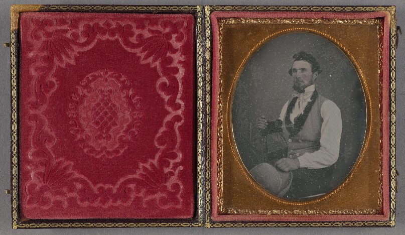 [Portrait of a bearded man seated, holding a hat]