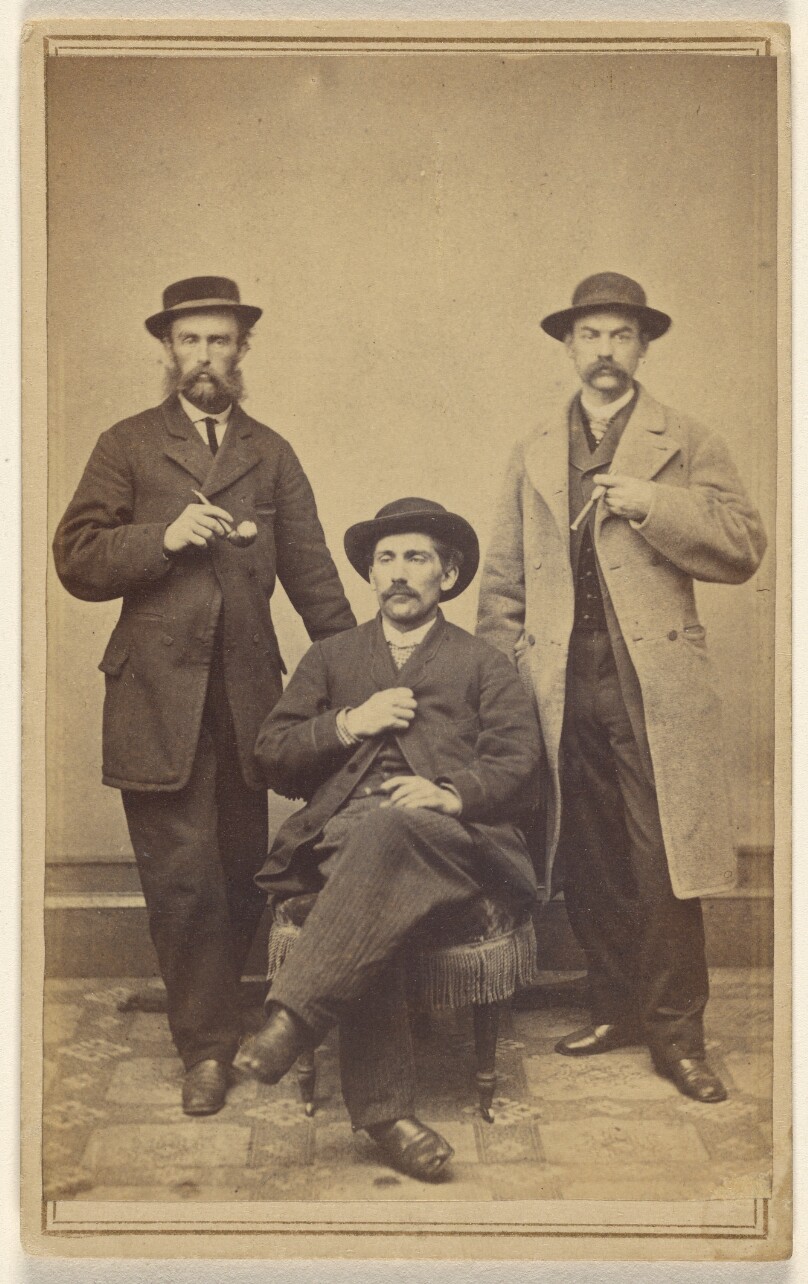 [Three unidentified men wearing hats, holding either a pipe or cigar, all with moustaches and/or beards]