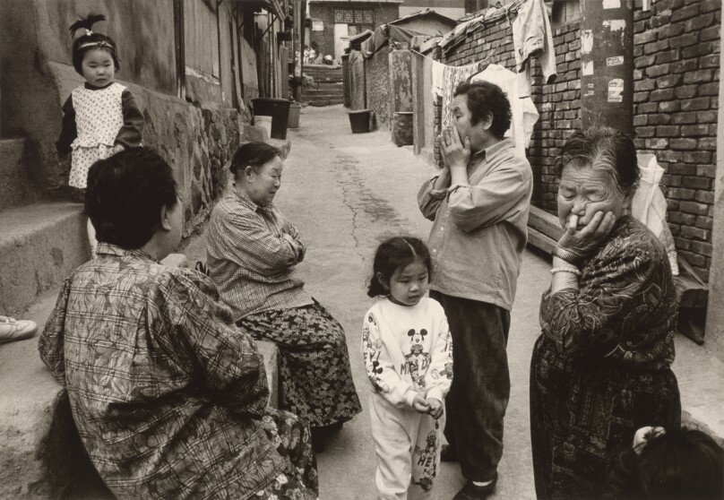 [Group of Four Women and Two Young Girls Conversing in an Alley]