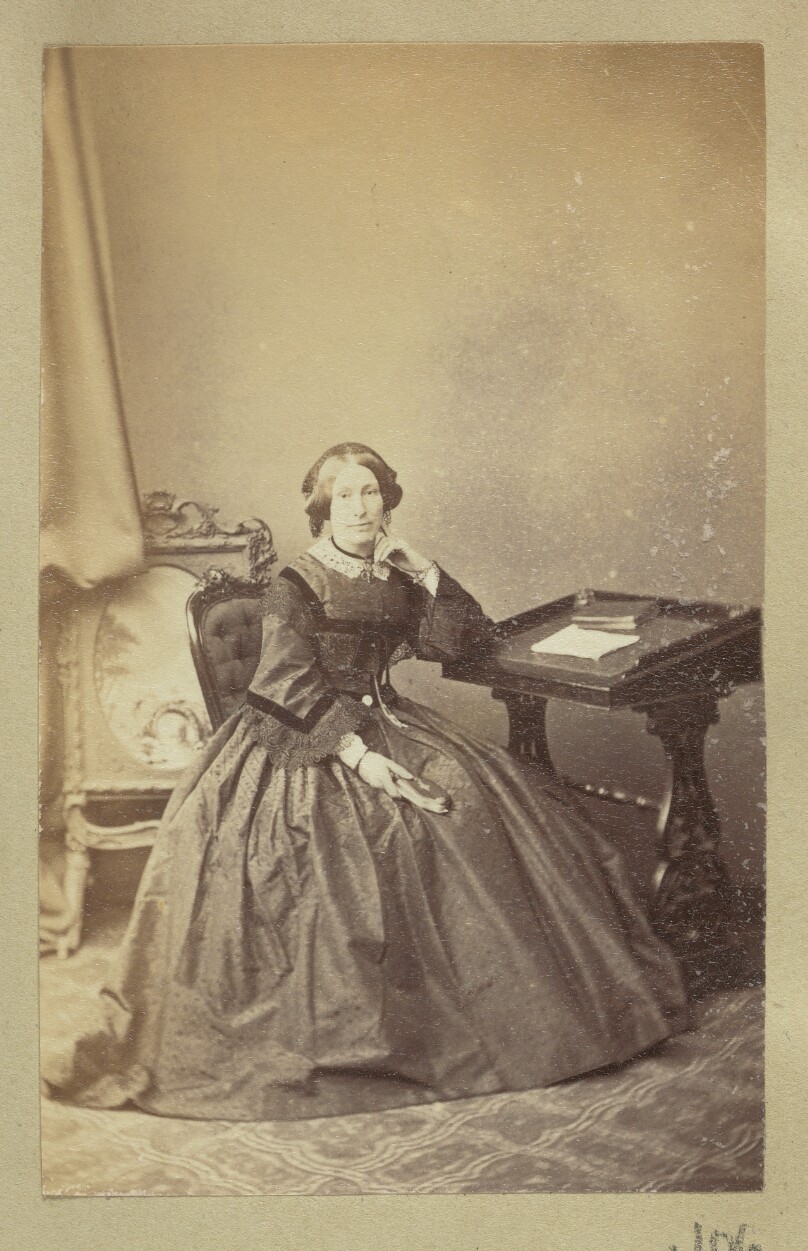 [Portrait of woman sitting next to writing desk]
