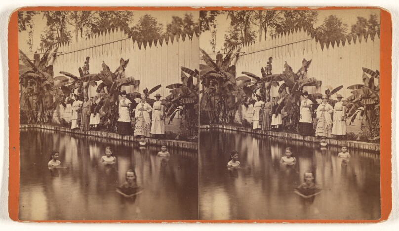 [Children in a backyard swimming pool, group of mothers at edge of pool observing, area enclosed with fence and banana trees]