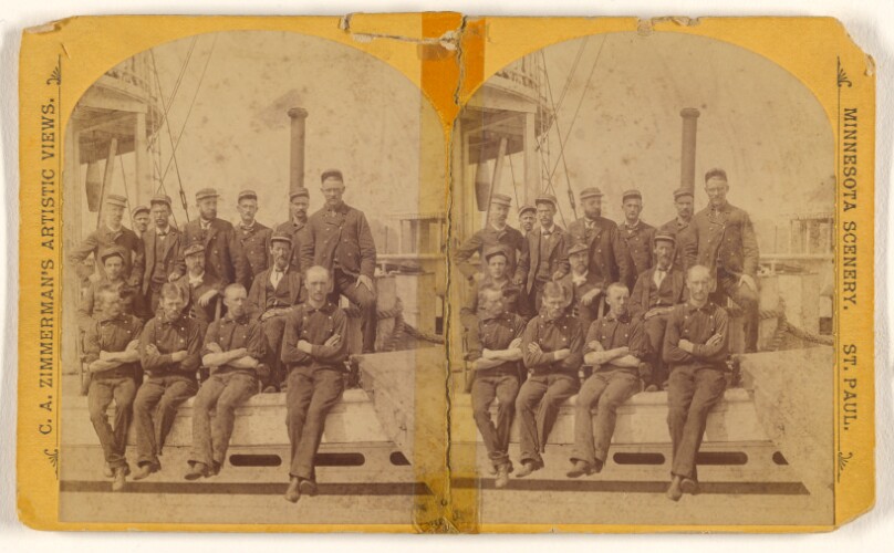 [Group of men posed on bow of a steamboat]