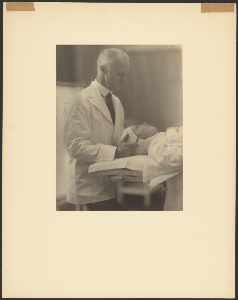 [Doctor in Lab Coat Holding Scapel to Patient's Head]