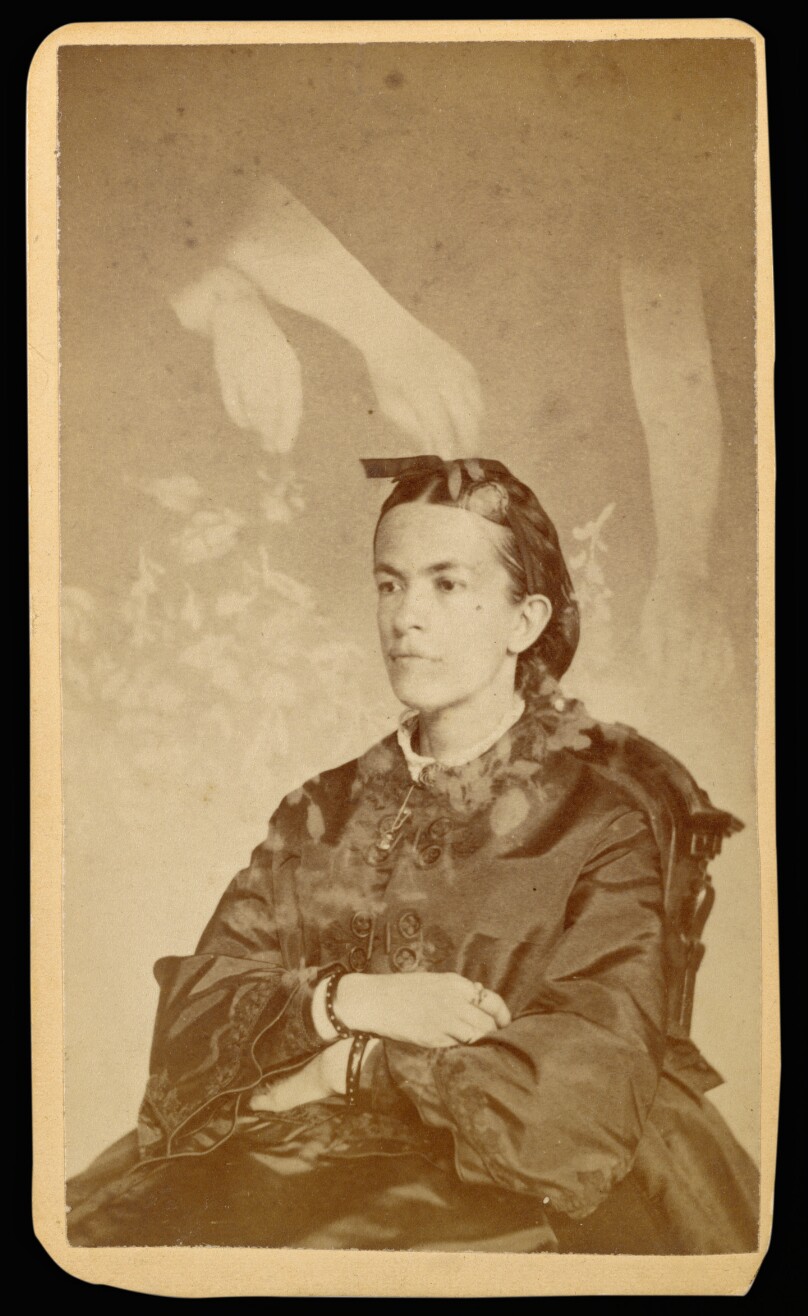 [Unidentified woman seated with arms of a "spirit" over her head]