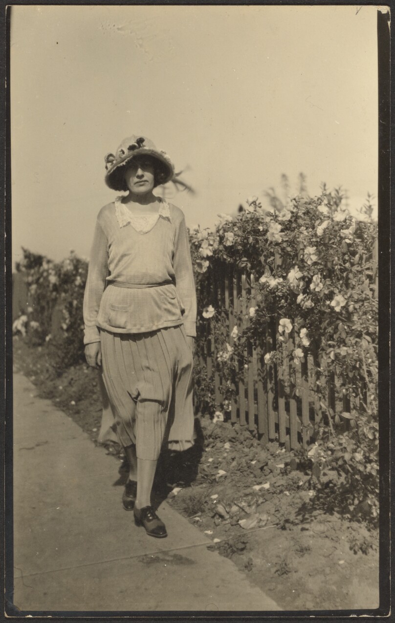 [Woman Walking Along Fence with Flowers]