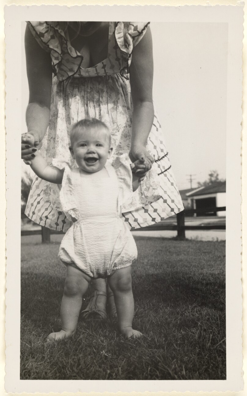 [Woman helping baby stand]