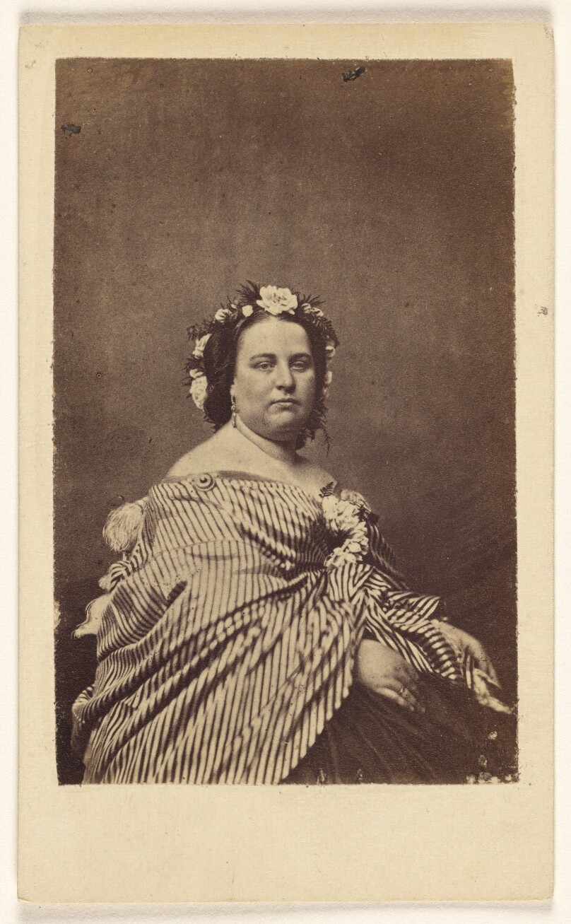[Unidentified woman wearing a flowered hat and striped shawl, seated]
