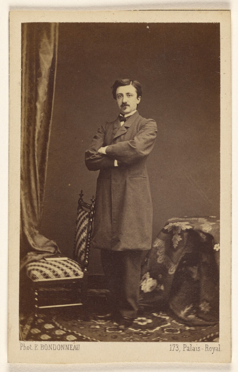[Unidentified man with moustache, standing with arms crossed]