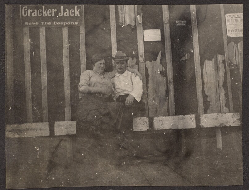 [Man and woman sitting on a wooden bench]