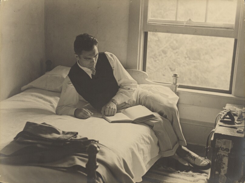 [World Heavyweight Boxer Max Schmeling Reading a Book While Sitting on the Edge of a Bed]