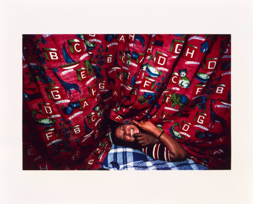 Kamla Laughing with a Customer, Peeks from under Her Alphabet Curtain