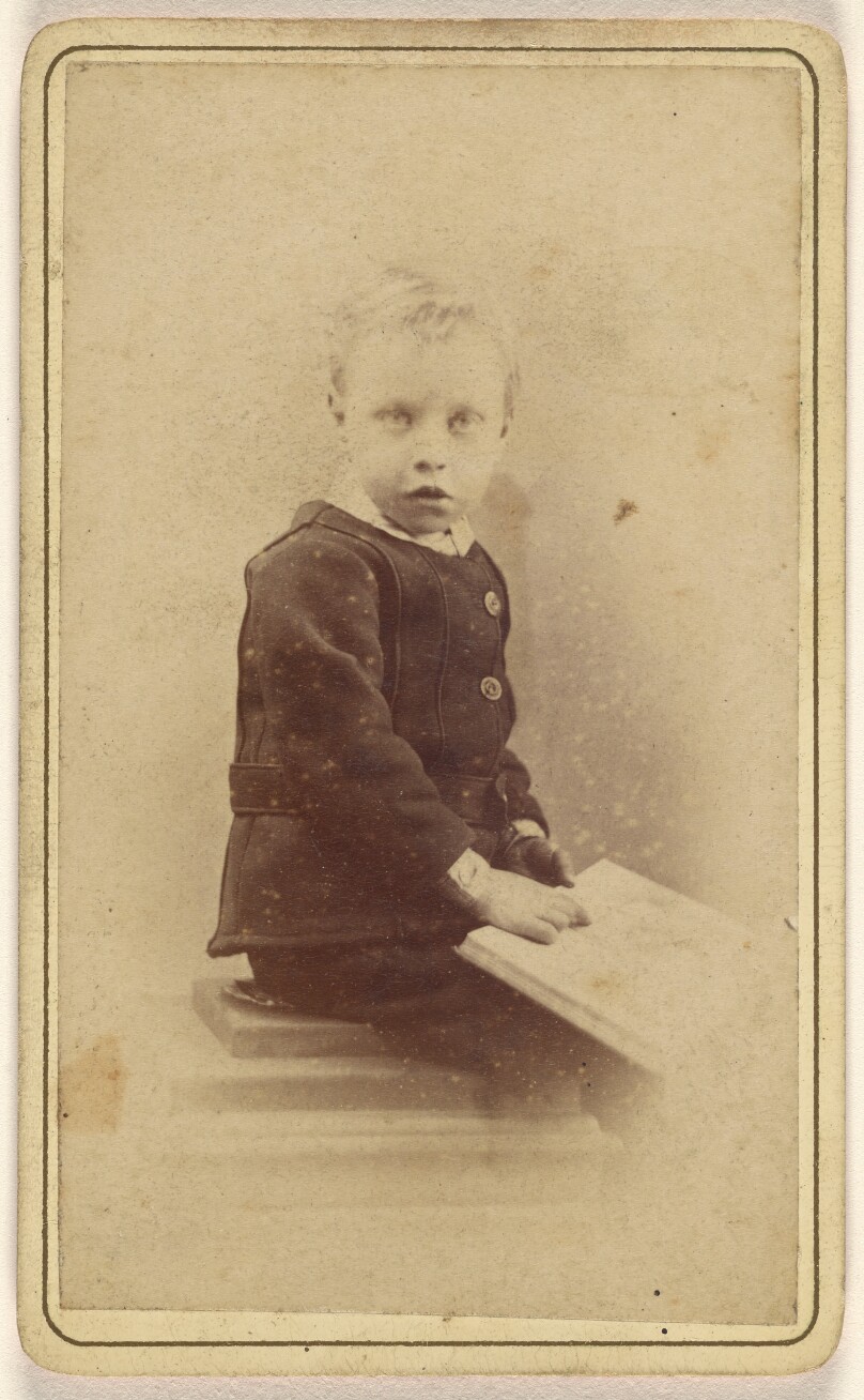 [Unidentified little boy seated with an open book on his lap]