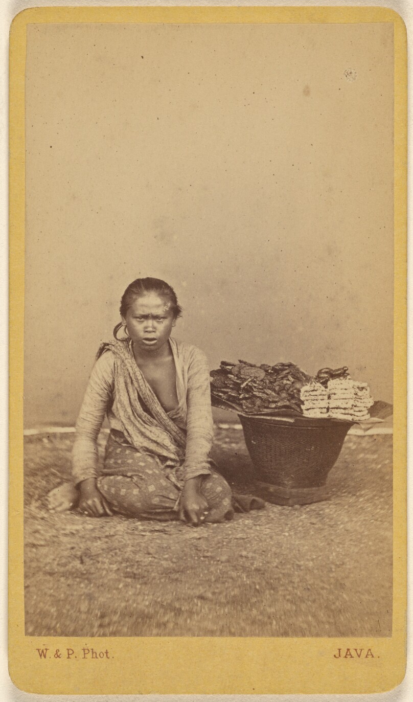 [Javanese woman seated with legs crossed, basket at side]